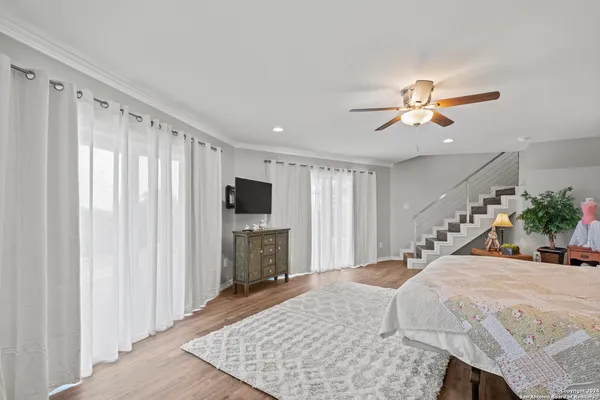 a bedroom with a bed a flat screen tv and a chandelier