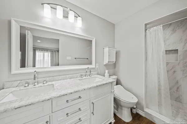 a bathroom with a granite countertop sink toilet and shower