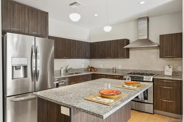 a kitchen with stainless steel appliances granite countertop a refrigerator a sink and a stove
