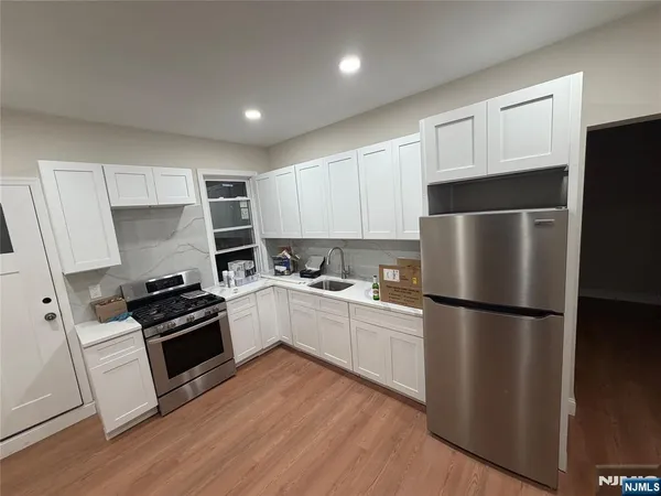 a kitchen with a refrigerator a stove top oven and wooden floor