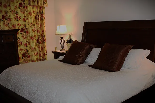 a black bed sitting in a bedroom next to a lamp