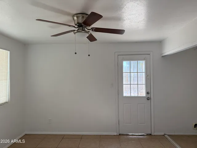 an empty room with windows and fan