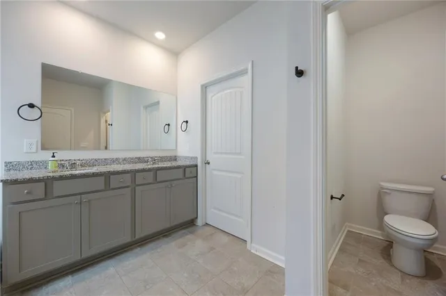 a spacious bathroom with a granite countertop sink a toilet and a mirror