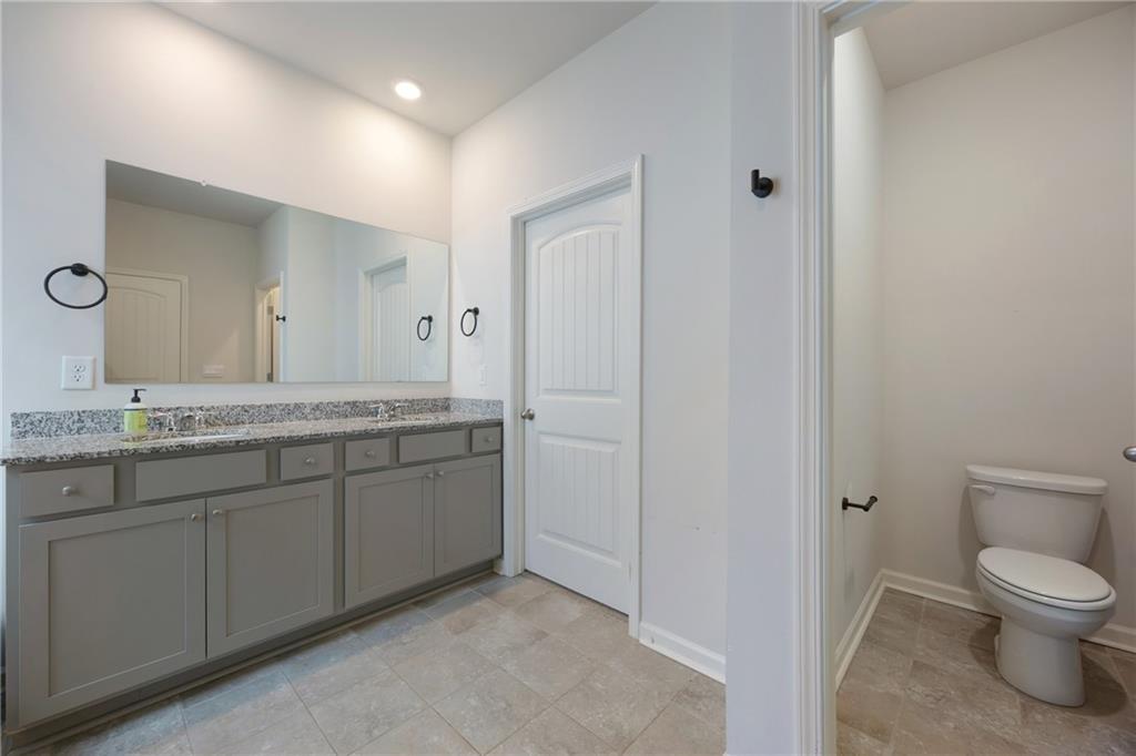 7571 Deerridge Way Fairburn, GA 30213 - Photo 15 of 26 a spacious bathroom with a granite countertop sink a toilet and a mirror