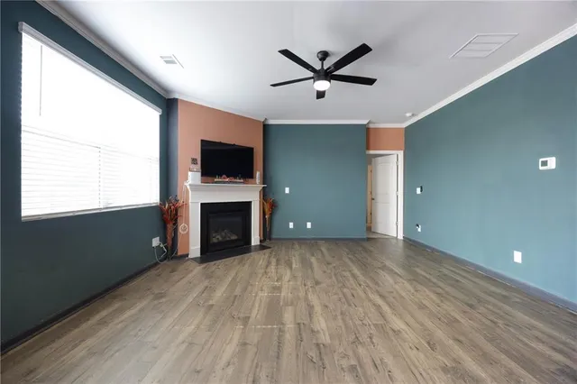 a view of a livingroom with a fireplace a ceiling fan and windows