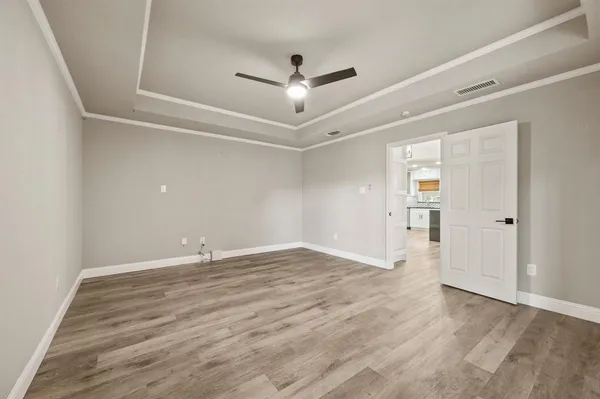 an empty room with wooden floor and ceiling fan