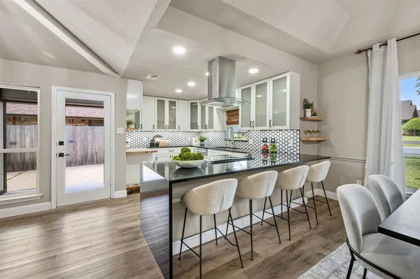 a kitchen with stainless steel appliances granite countertop a dining table chairs and view living room