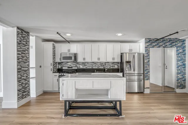 a kitchen with granite countertop white cabinets and stainless steel appliances