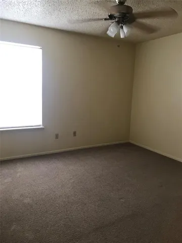 an empty room with a fan & a window