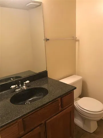 a bathroom with a granite countertop sink and a toilet