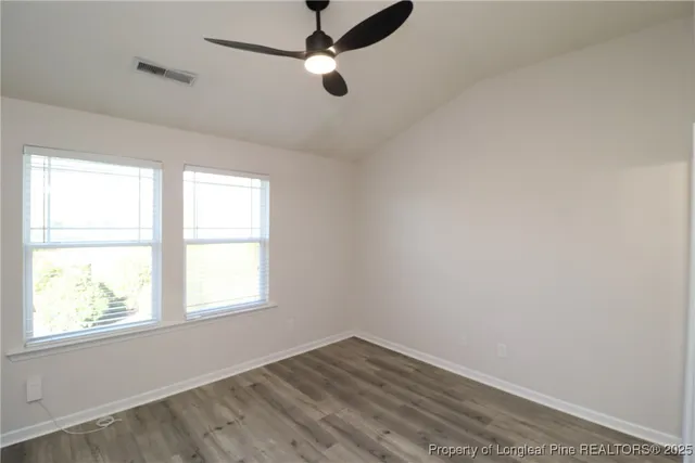 an empty room with wooden floor cabinet and windows