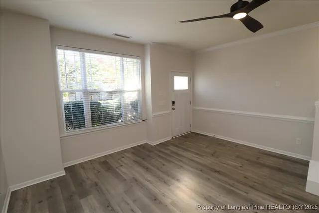 an empty room with wooden floor fan and windows