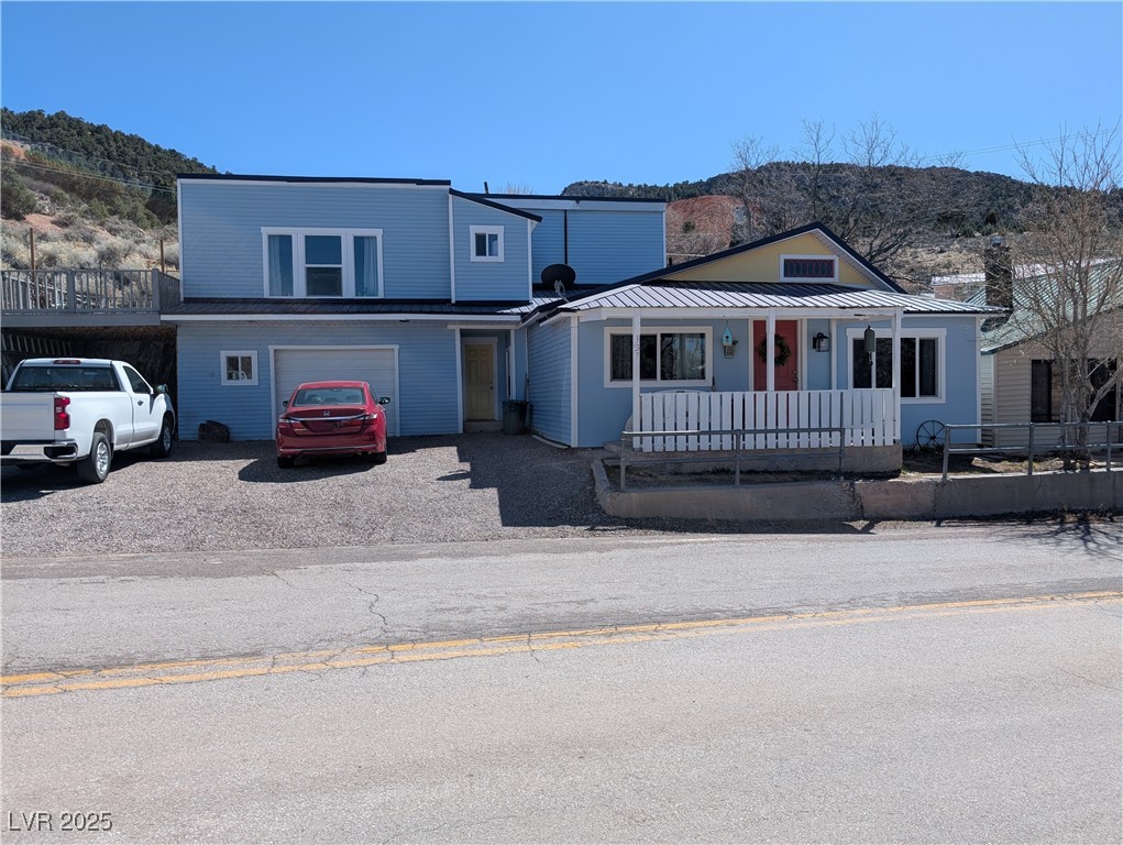 View of front of property with a mountain view, a porch, driveway, and an attached garage