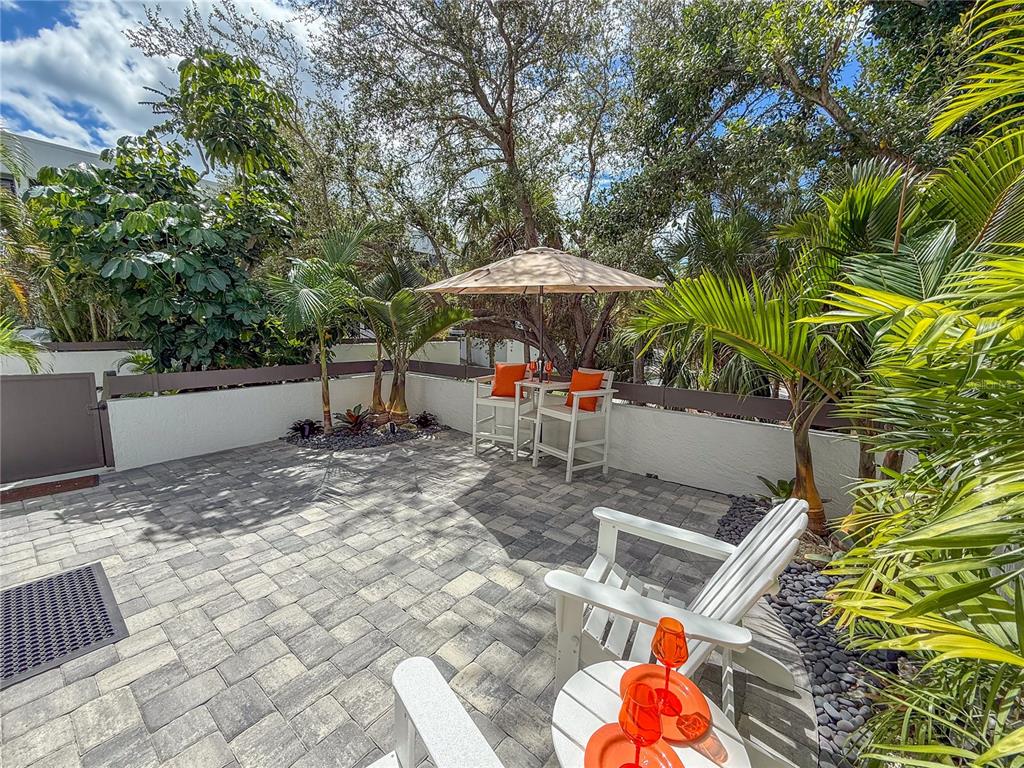 806 Bayport Way, Unit 806 Longboat Key, FL 34228 - Photo 43 of 79 a backyard of a house with table and chairs under an umbrella
