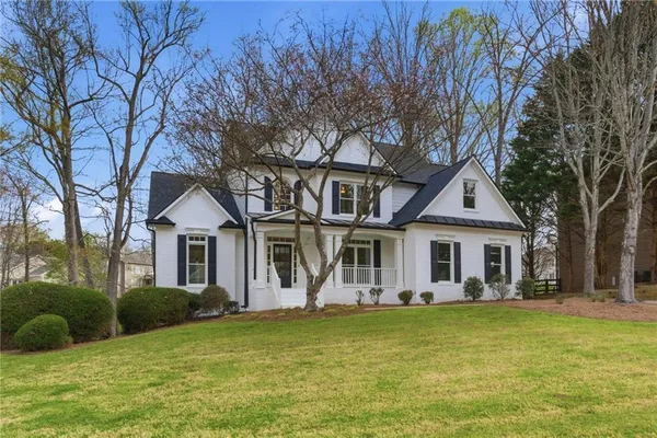 a front view of a house with a garden and trees