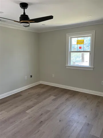 an empty room with wooden floor cabinet and windows