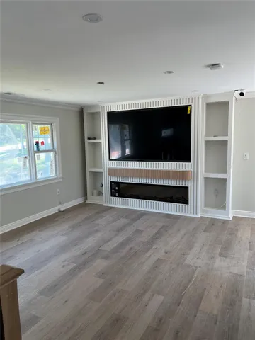 a view of an empty room with a window and wooden floor