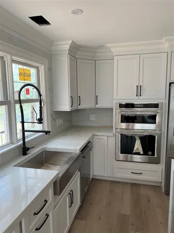 a kitchen with granite countertop white cabinets and stainless steel appliances