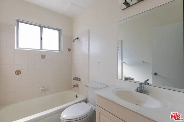 a bathroom with a bathtub shower sink vanity mirror and toilet
