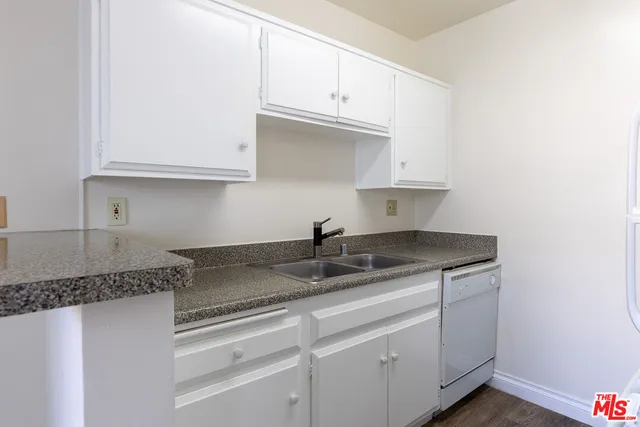 a kitchen with granite countertop white cabinets and a sink