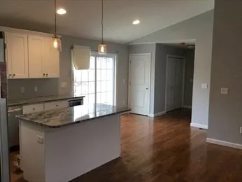 a kitchen with stainless steel appliances granite countertop a sink a stove and a wooden floor