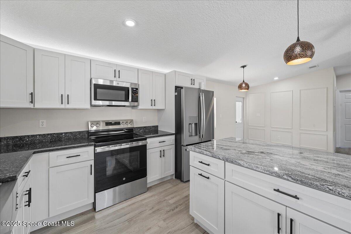 1924 Big Cypress Street Northeast Palm Bay, FL 32905 - Photo 13 of 29 a kitchen with kitchen island granite countertop appliances cabinets a sink and a counter top space