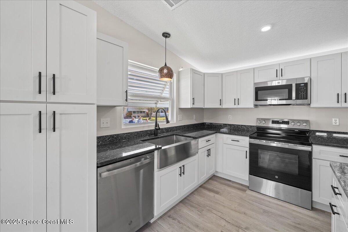 1924 Big Cypress Street Northeast Palm Bay, FL 32905 - Photo 14 of 29 a kitchen with stainless steel appliances granite countertop a stove a sink and a microwave