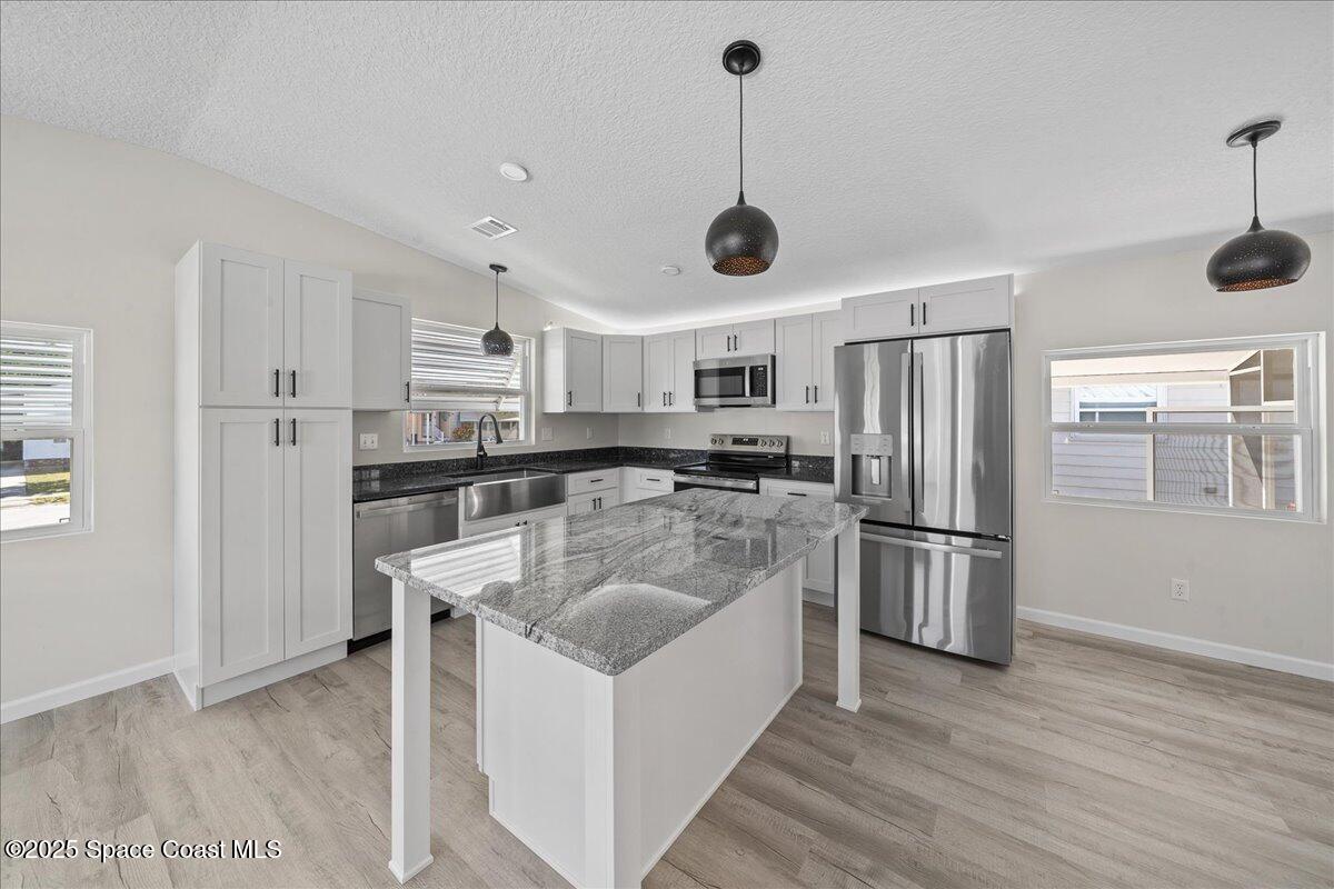 1924 Big Cypress Street Northeast Palm Bay, FL 32905 - Photo 16 of 29 a kitchen with stainless steel appliances granite countertop a refrigerator a oven a sink a stove and white cabinets with wooden floor