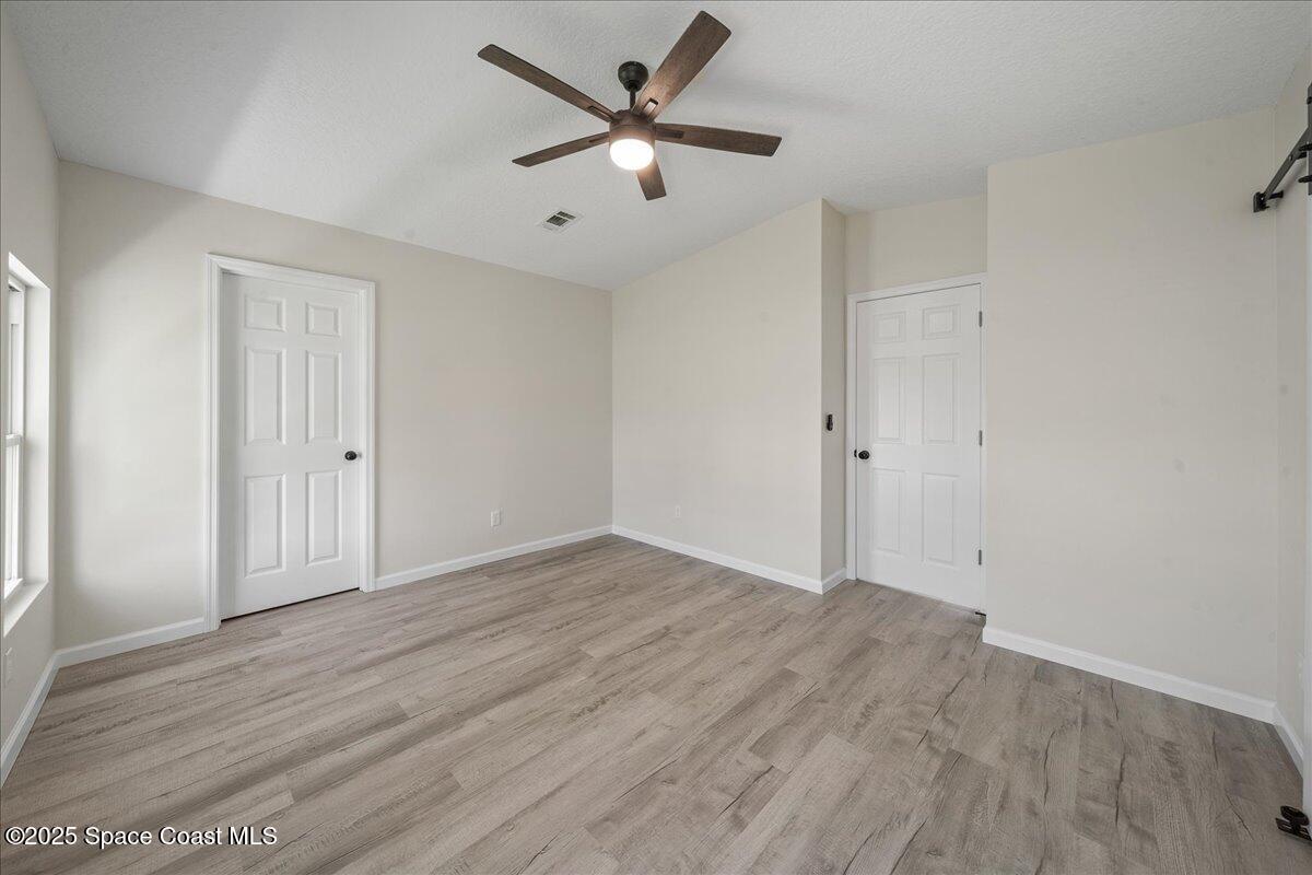 1924 Big Cypress Street Northeast Palm Bay, FL 32905 - Photo 20 of 29 an empty room with wooden floor and ceiling fan