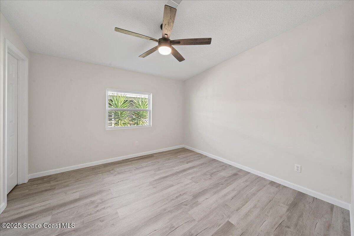 1924 Big Cypress Street Northeast Palm Bay, FL 32905 - Photo 23 of 29 an empty room with wooden floor fan and windows