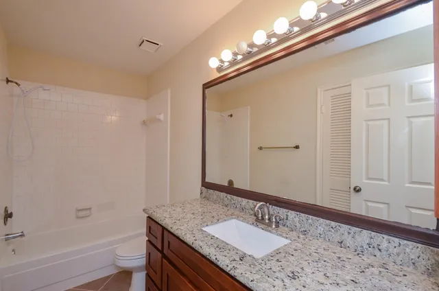 a bathroom with a granite countertop sink a toilet and shower