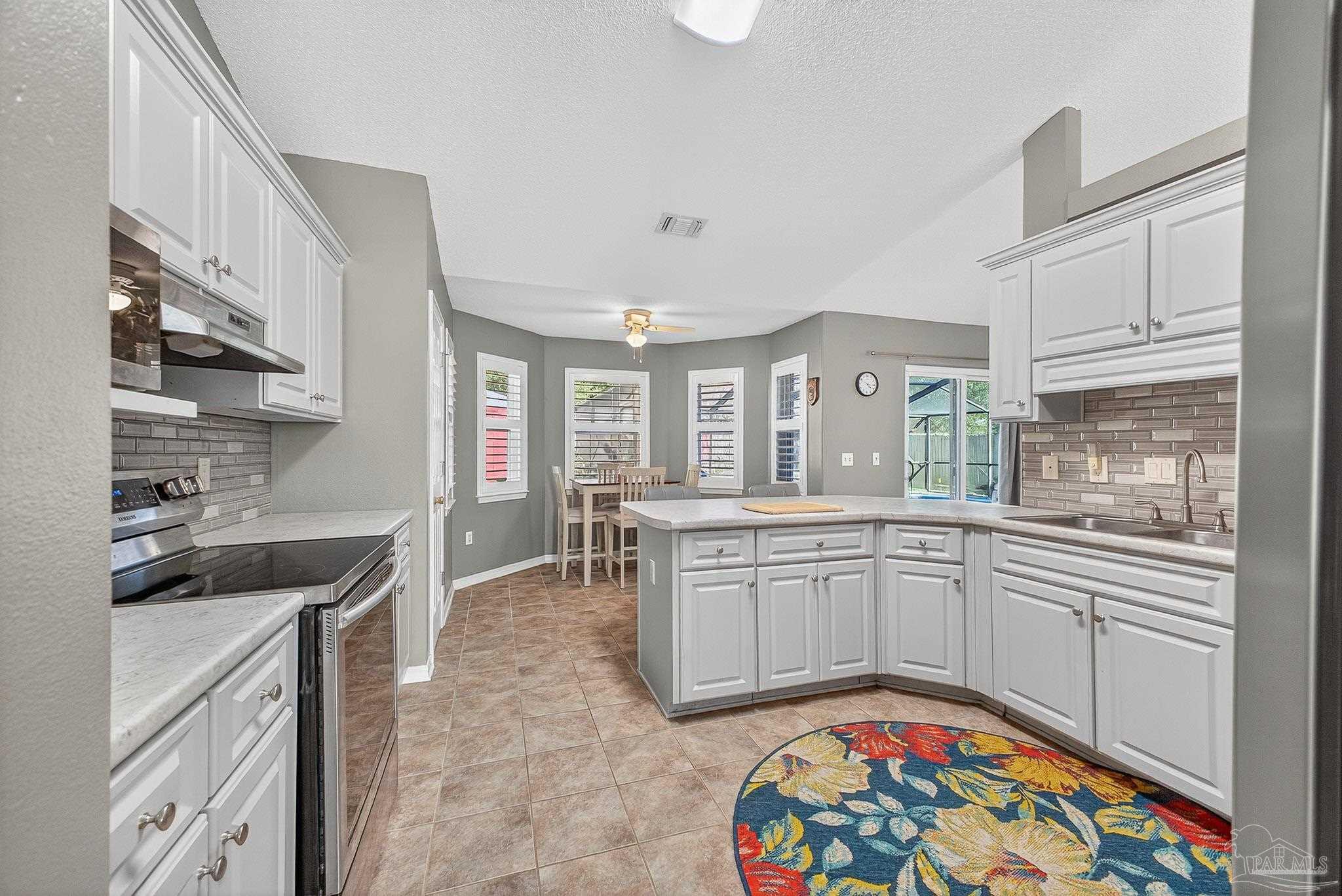 4650 Ridge Pointe Drive Pace, FL 32571 - Photo 16 of 38 a large white kitchen with stainless steel appliances granite countertop a sink and dishwasher a stove top oven with wooden floor