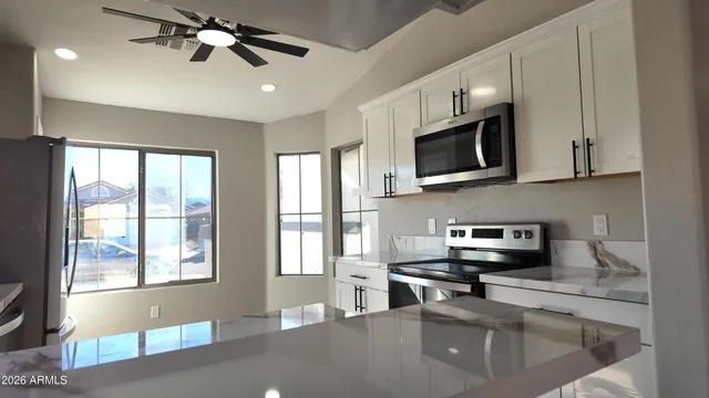 a kitchen with stainless steel appliances a microwave a stove and white cabinets
