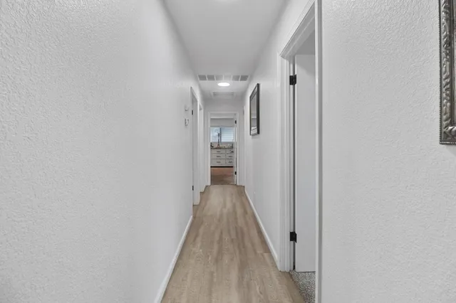 a view of a hallway with wooden floor and a bathroom