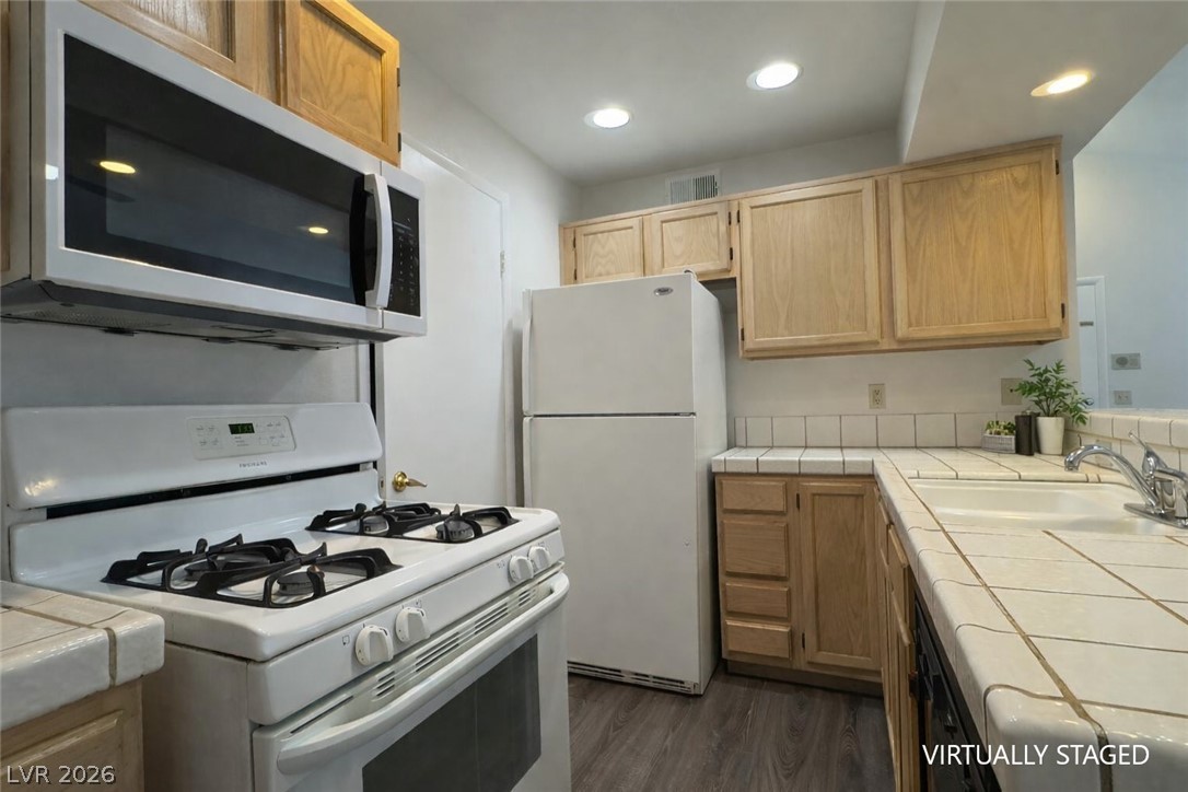 7570 West Flamingo Road, Unit 209 Las Vegas, NV 89147 - Photo 11 of 30 Kitchen featuring tile countertops, white appliances, light wood finish cabinets, dark wood-style flooring, and recessed lighting
