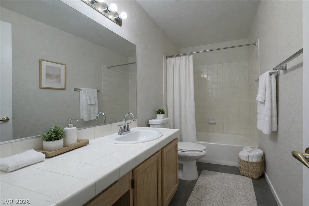 7570 West Flamingo Road, Unit 209 Las Vegas, NV 89147 - Photo 15 of 30 Bathroom with vanity, shower / bathtub combination with curtain, and dark tile patterned floors