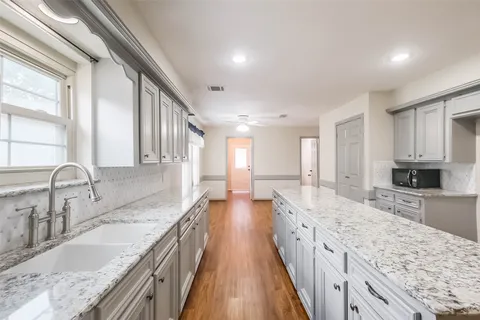 a large kitchen with granite countertop a large counter top a sink stainless steel appliances and cabinets