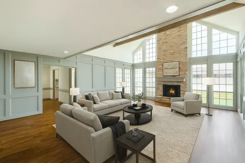 a living room with furniture large window and wooden floor