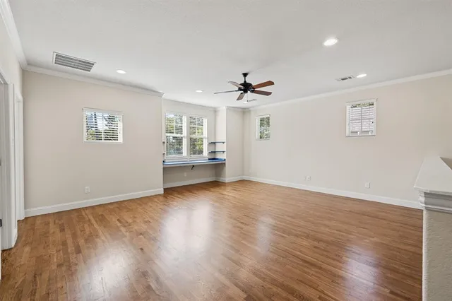 a view of an empty room with a window and wooden floor
