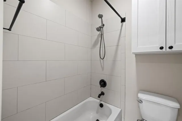 a bathroom with a bathtub shower and toilet
