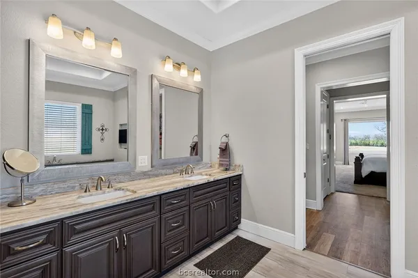a en suite bathroom with a granite countertop double vanity sink and a mirror
