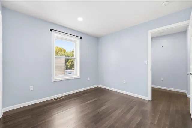 an empty room with wooden floor and a window