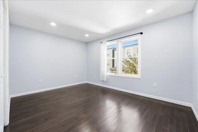 an empty room with wooden floor and window