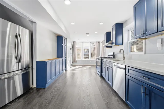 a large kitchen with stainless steel appliances wooden floors and wooden cabinets
