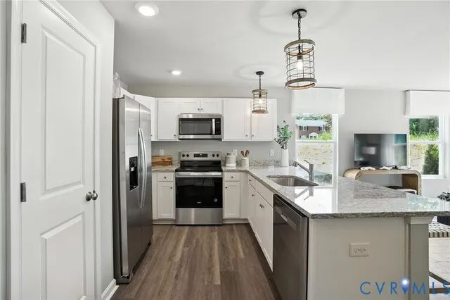 a kitchen with kitchen island granite countertop stainless steel appliances a sink a stove a refrigerator cabinets and a window