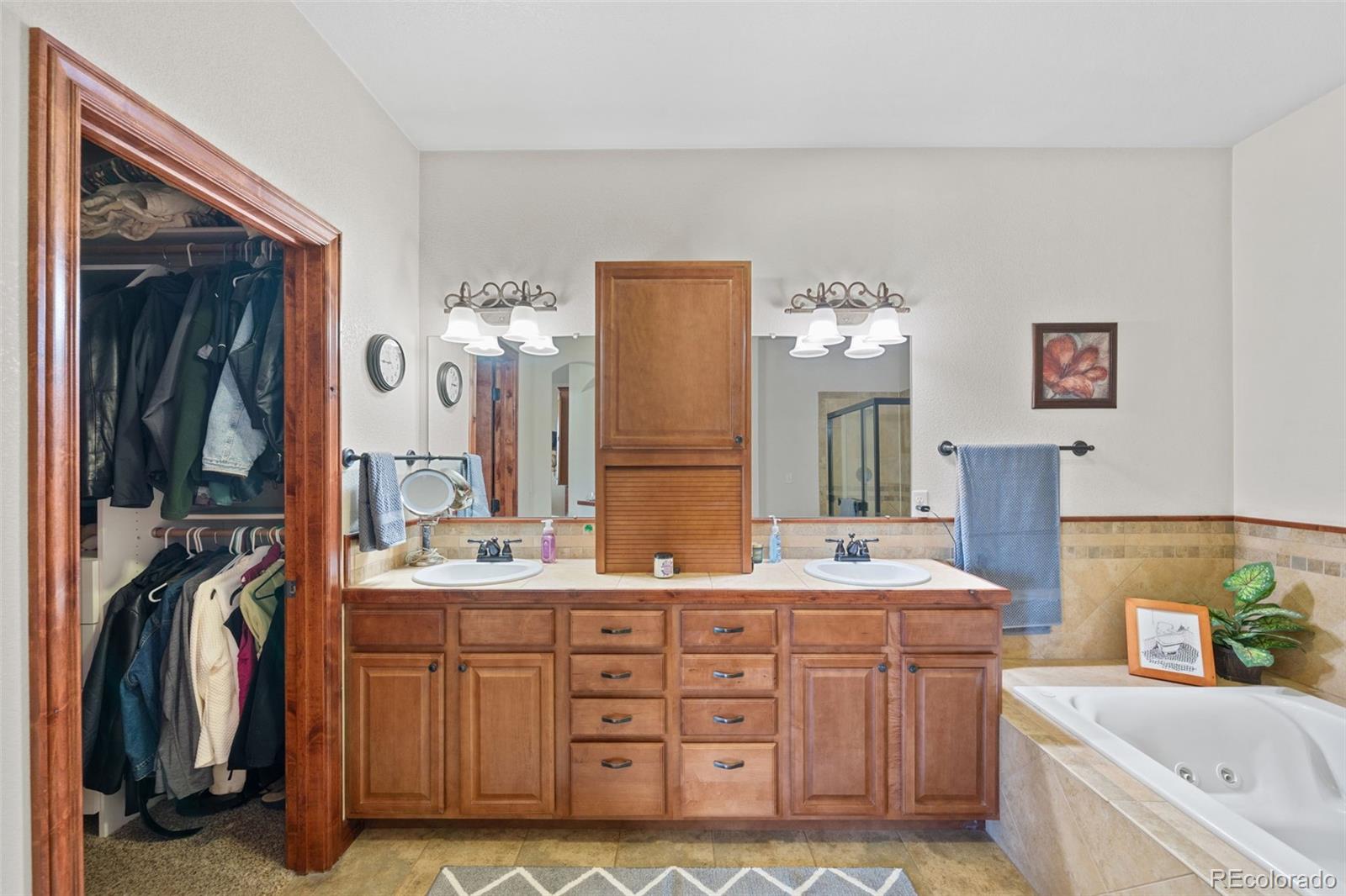 1731 Wales Drive Berthoud, CO 80513 - Photo 16 of 36 a bathroom with a double vanity sink a two mirror a bathtub and a double vanity sink