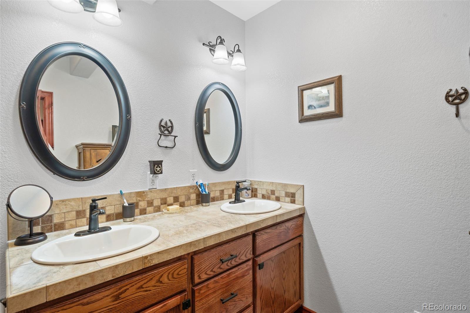 1731 Wales Drive Berthoud, CO 80513 - Photo 30 of 36 a bathroom with a granite countertop double vanity sink and a mirror