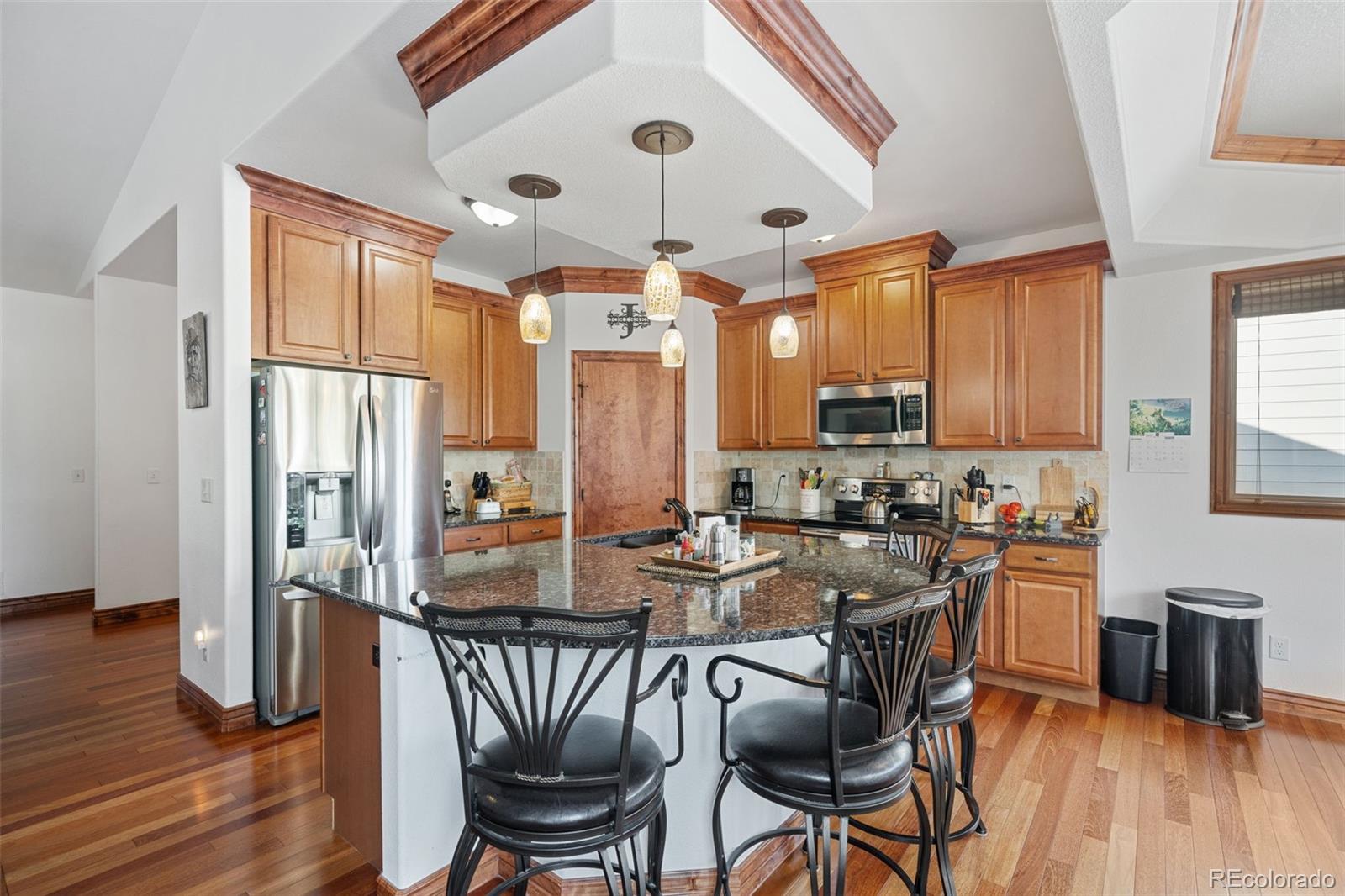 1731 Wales Drive Berthoud, CO 80513 - Photo 10 of 36 a kitchen with stainless steel appliances granite countertop table chairs stove and wooden floor