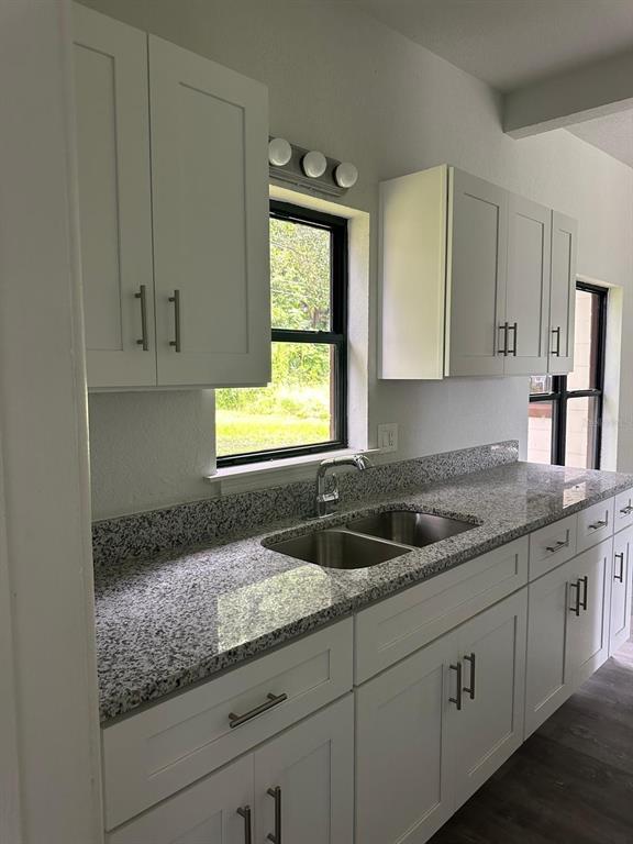 4514 Arch Street Orlando, FL 32808 - Photo 3 of 21 a kitchen with granite countertop a sink window and cabinets