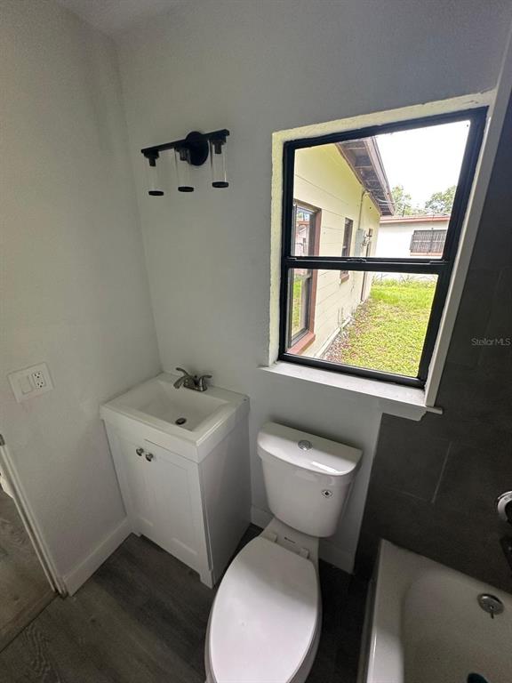 4514 Arch Street Orlando, FL 32808 - Photo 10 of 21 a bathroom with a toilet sink and mirror next to a window